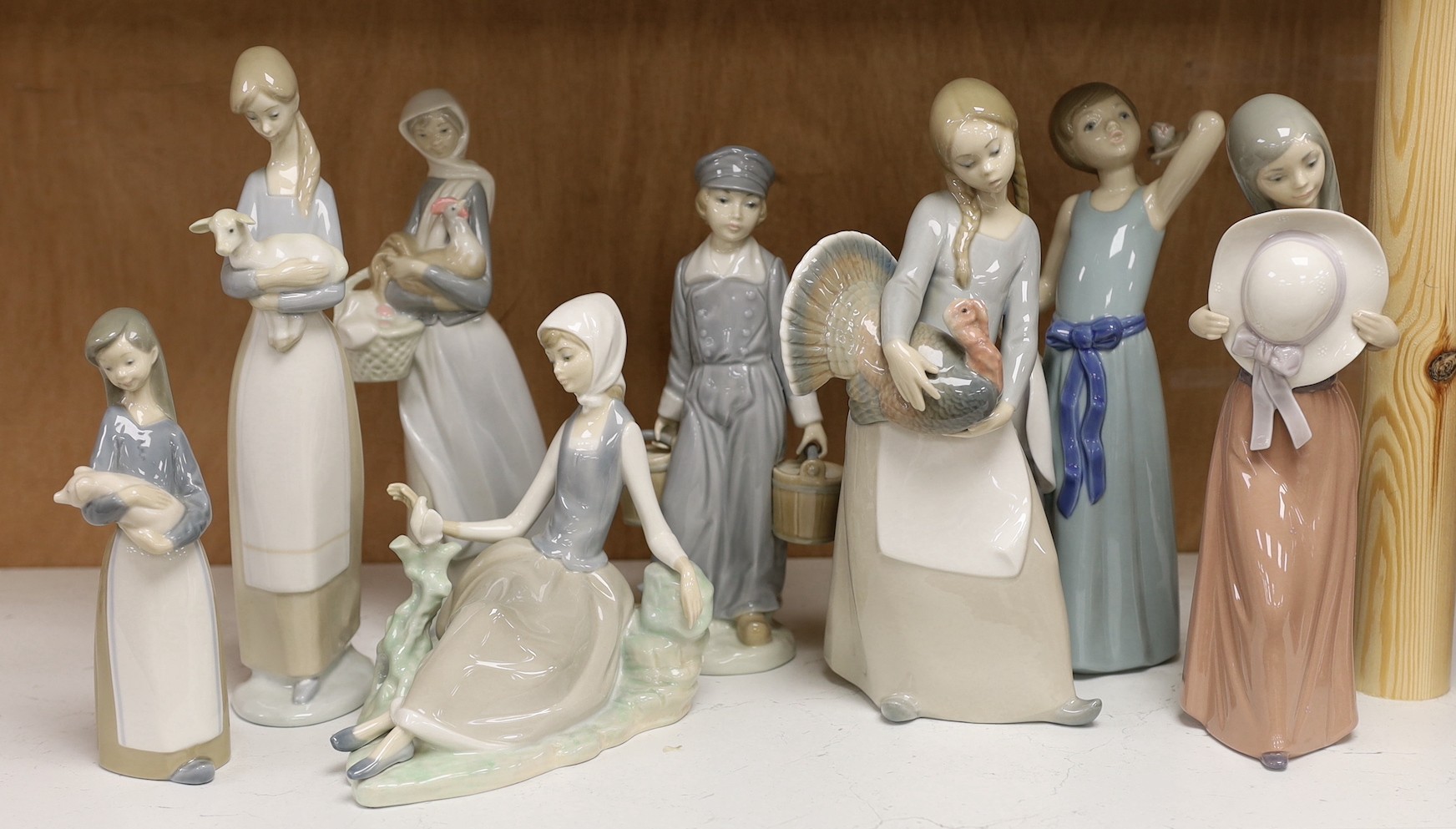 A collection of eight various Lladro figure groups to include a girl with lamb, a seated girl, etc- tallest girl holding a turkey 25 cms high.